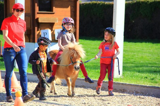 Ein  Kind wird auf einem Pony von anderen Kindern geführt